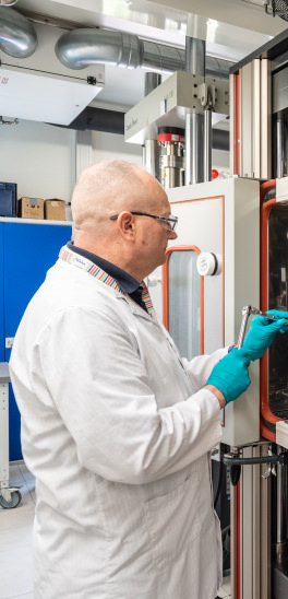 Researcher in white lab coat operating battery technology in WMG's Energy Innovation Centre.