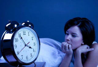 A woman looks at a clock from bed