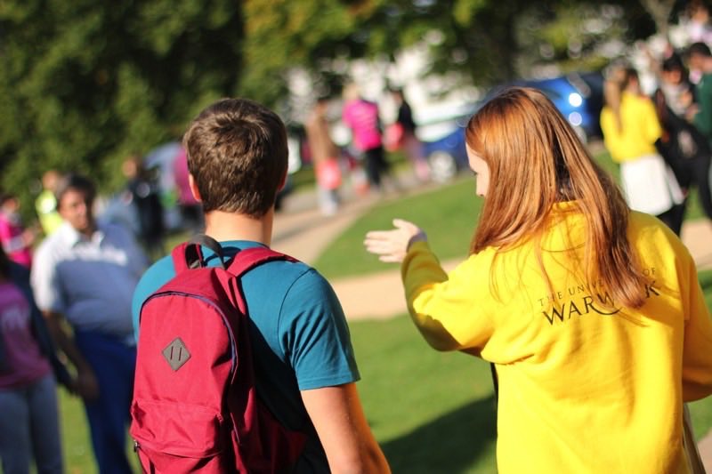 A student volunteer in a yellow jumper directing visitors
